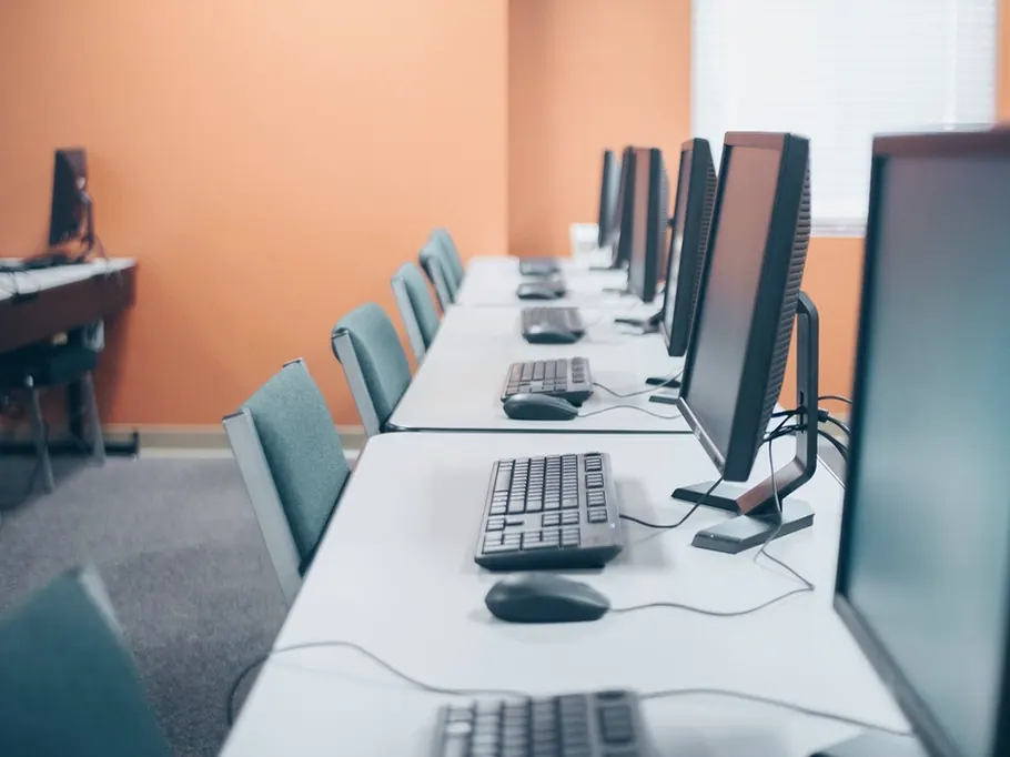 A row of desktop computers in an empty computer suite